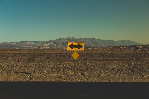 a road yellow road sign pointing to the left and right