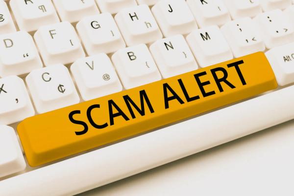 yellow space bar on keyboard with words "scam alert" in black